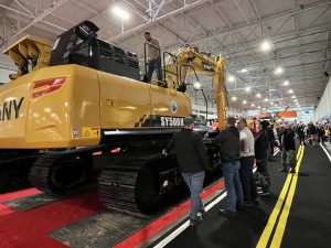 Men talking inside an equipment trade event for heavy machinery.